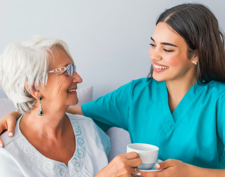 caregiving giving a tea cup to senior
