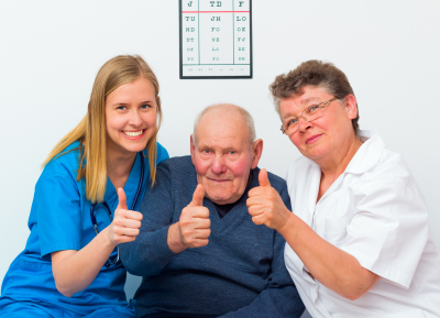 senior showing thumbs up with his caregivers.