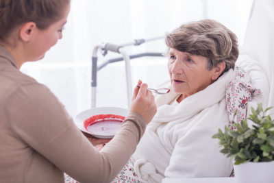 female caregiver assisting senior woman in eating